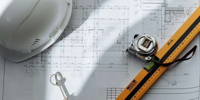 Picture of a construction hat and Macon housing district blueprint resting on a table